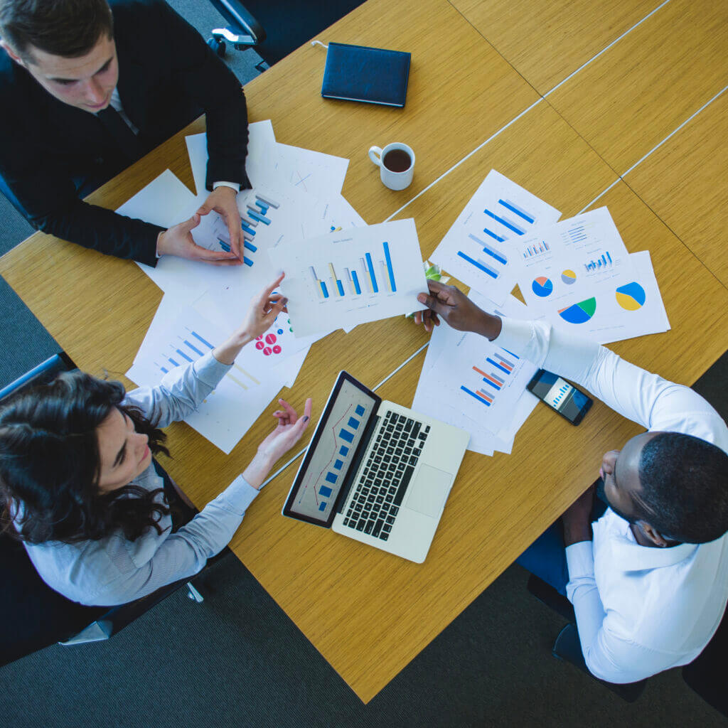 Healthcare professionals engaged in a strategic meeting, analyzing RCM KPI reports on a laptop and printed documents, embodying RSB Healthcare Consulting’s commitment to delivering customized, data-driven solutions for financial excellence in healthcare