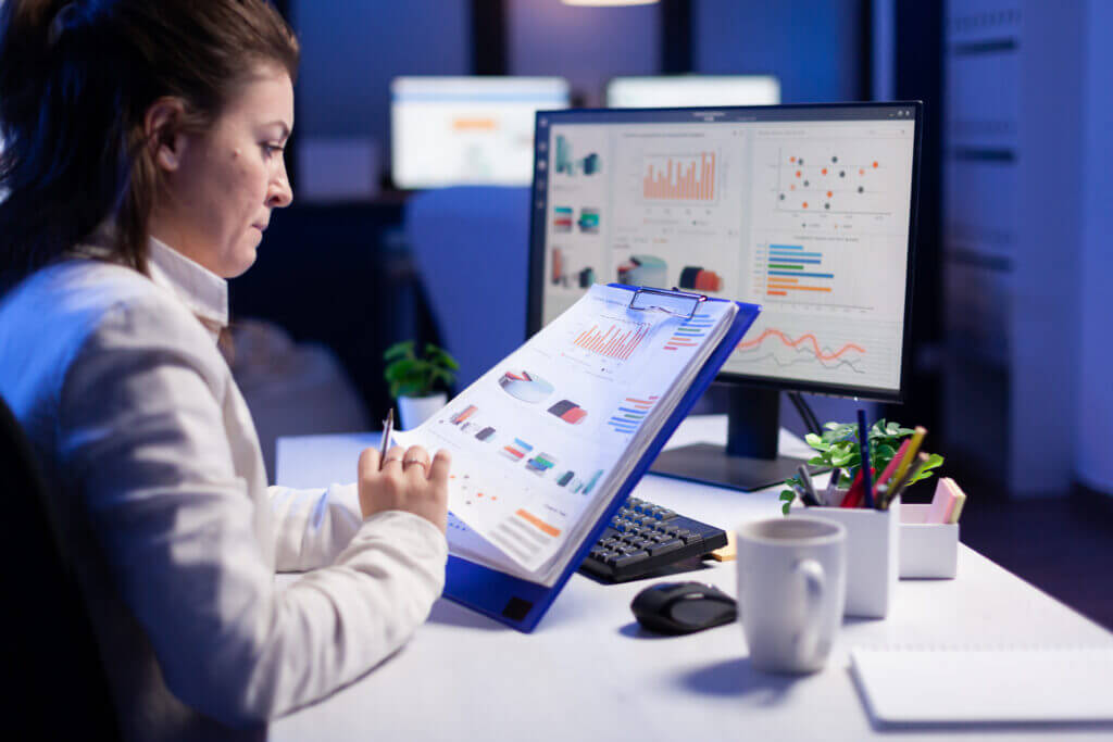 Focused healthcare professional analyzing revenue cycle reports on multiple monitors, showcasing the critical role of data in optimizing financial performance and operational efficiency in the healthcare industry