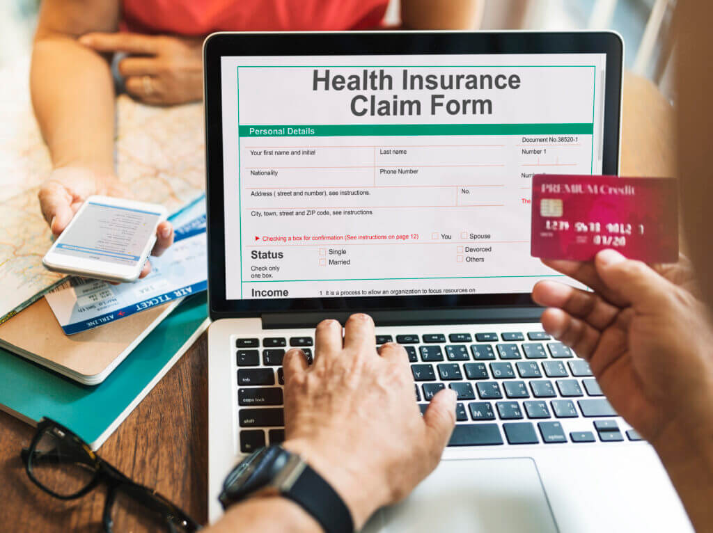 A person holding a health insurance card and a tablet displaying a Health Insurance Claim Form, symbolizing the process of claim submission and follow-up in healthcare services