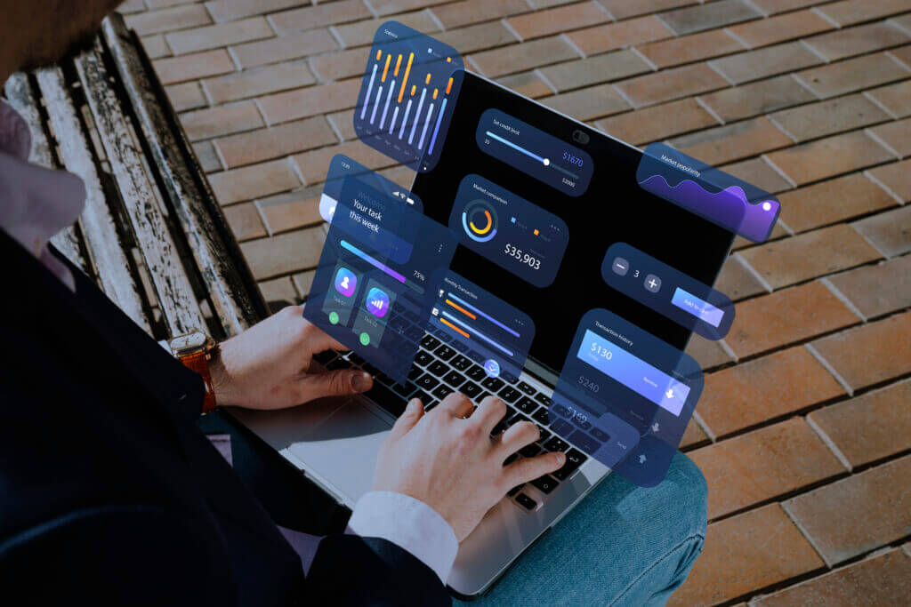 A person working on a laptop with augmented reality displays of various data integration interfaces floating above the keyboard, symbolizing advanced comprehensive data analytics from multiple sources