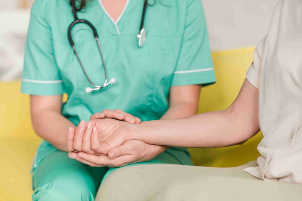 Healthcare professional holding a patient’s hands.